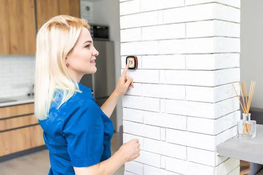 Woman standing in her home adjusting the thermostat